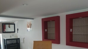 Un salon moderne avec un canapé beige, une petite table et une fenêtre à cadre rouge.
