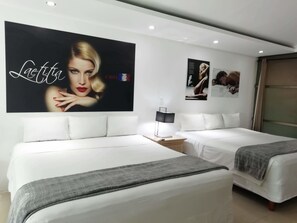 Une chambre d’hôtel avec deux lits, une table de chevet avec une lampe et une grande affiche au mur.
