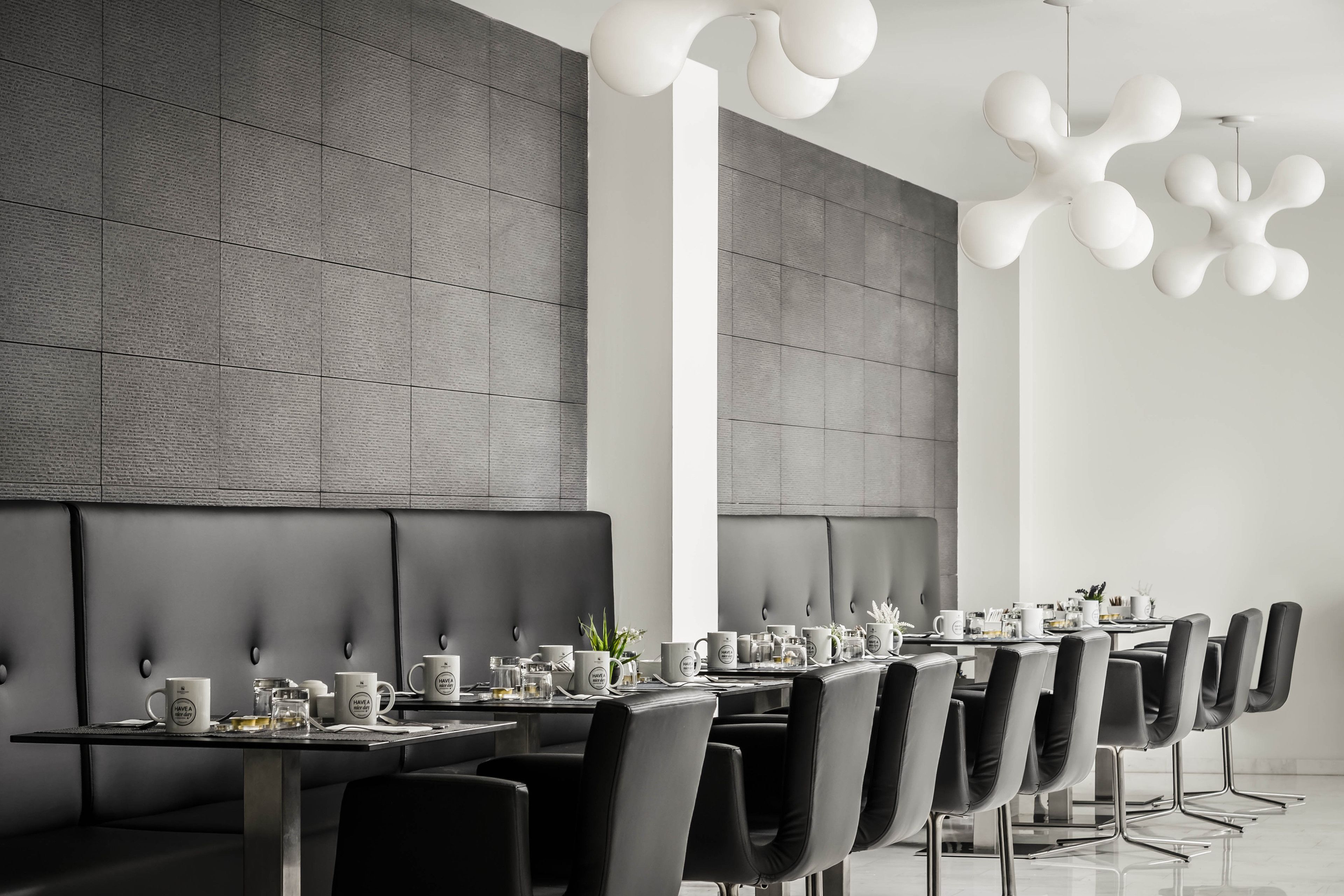 Un espace de salle à manger moderne avec une longue table, des chaises noires et un mur gris à texture.