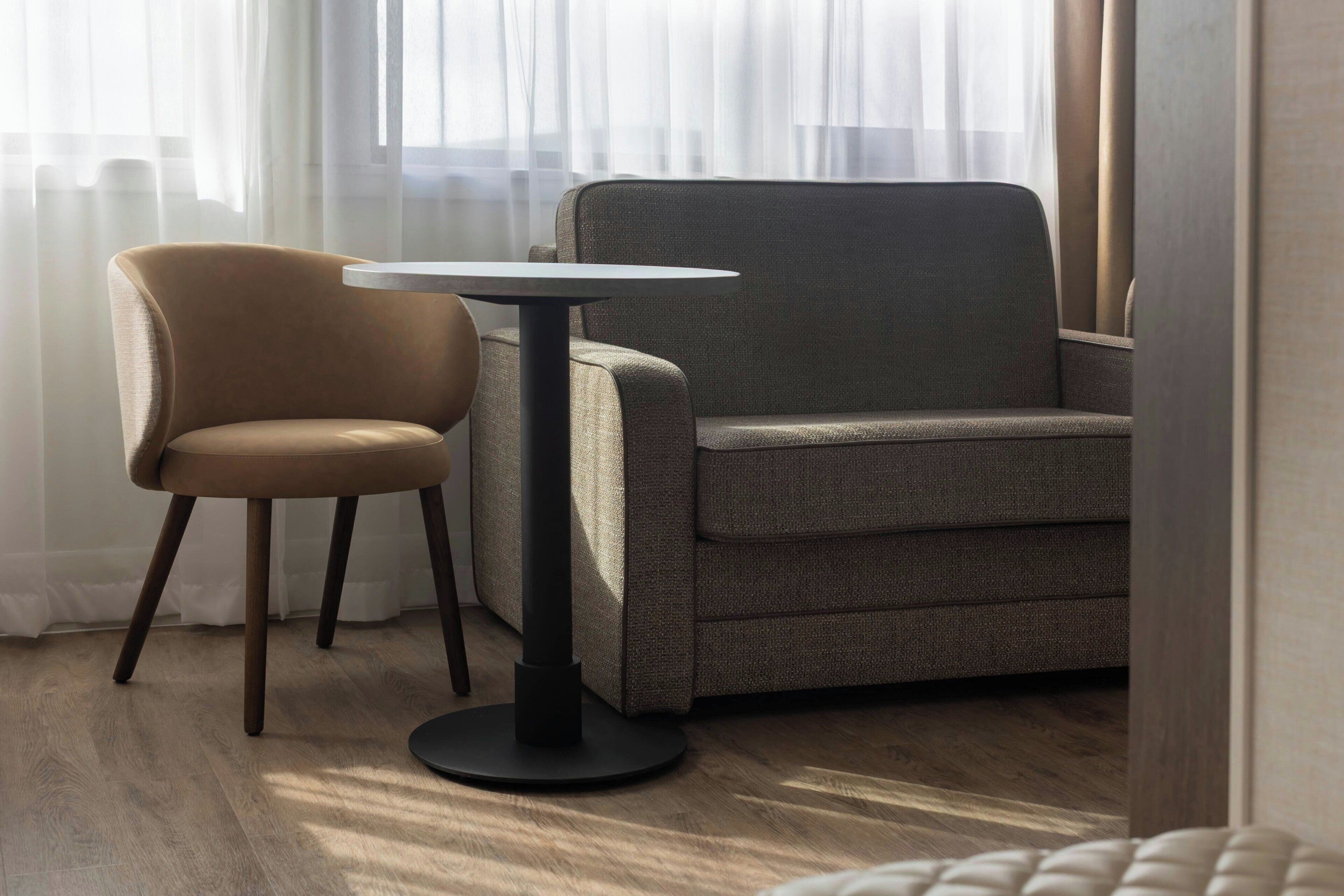 Een moderne kamer met een grijze bank, een ronde tafel en een stoel.