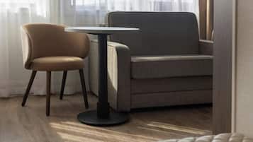 Een moderne kamer met een grijze bank, een ronde tafel en een stoel.