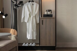 A bathroom with a robe hanging on a rack, a cabinet with a coffee maker, and slippers on the floor. - AC Hotel Birmingham NEC and Airport (Birmingham)