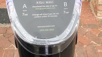 Une borne de recharge Pod Point, accompagnée d’instructions d’utilisation, notamment sur la manière de brancher le câble, de sélectionner la borne Pod Point dans l’application et de confirmer le démarrage de la recharge.