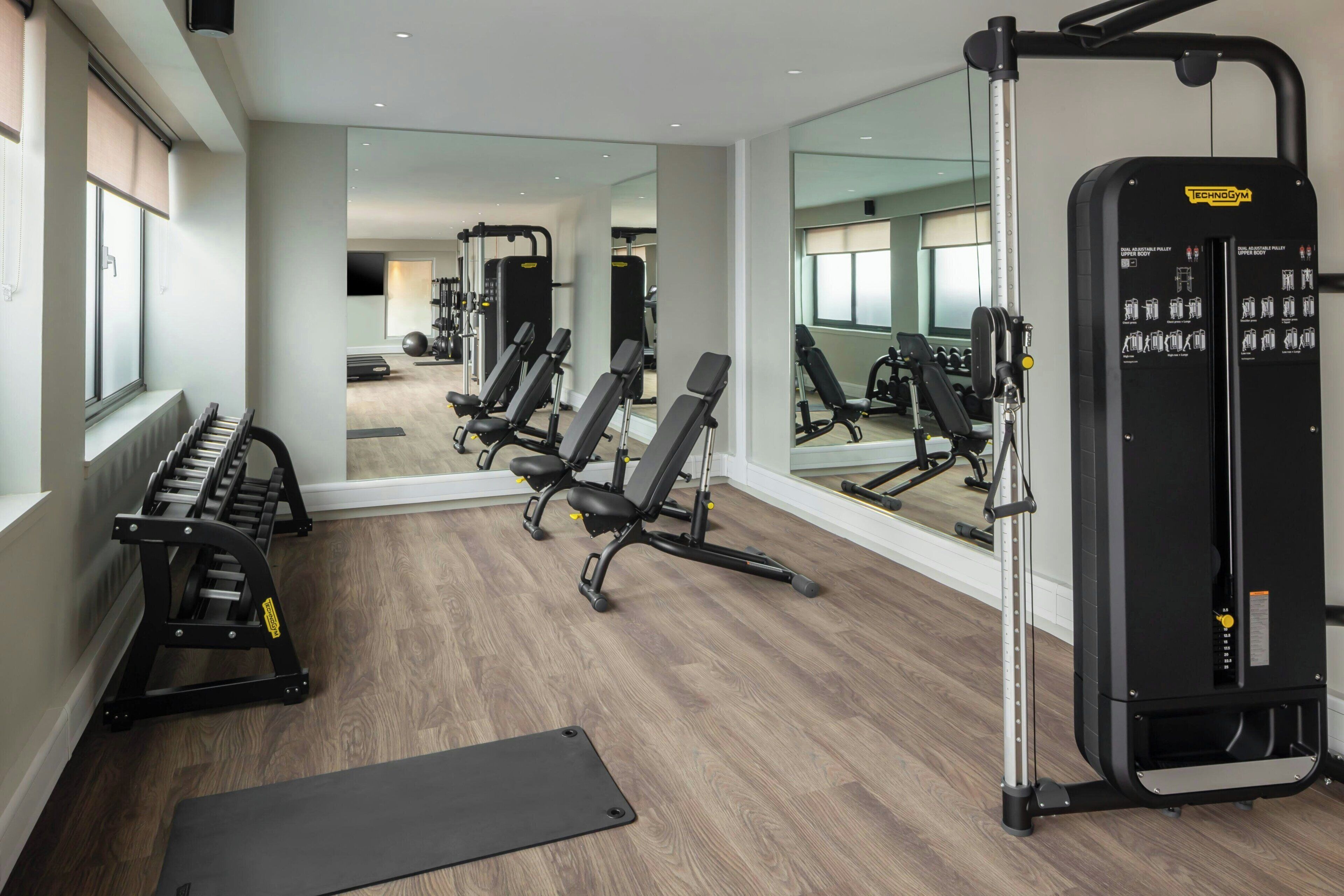 A gym with exercise equipment, a mirror, and a window.