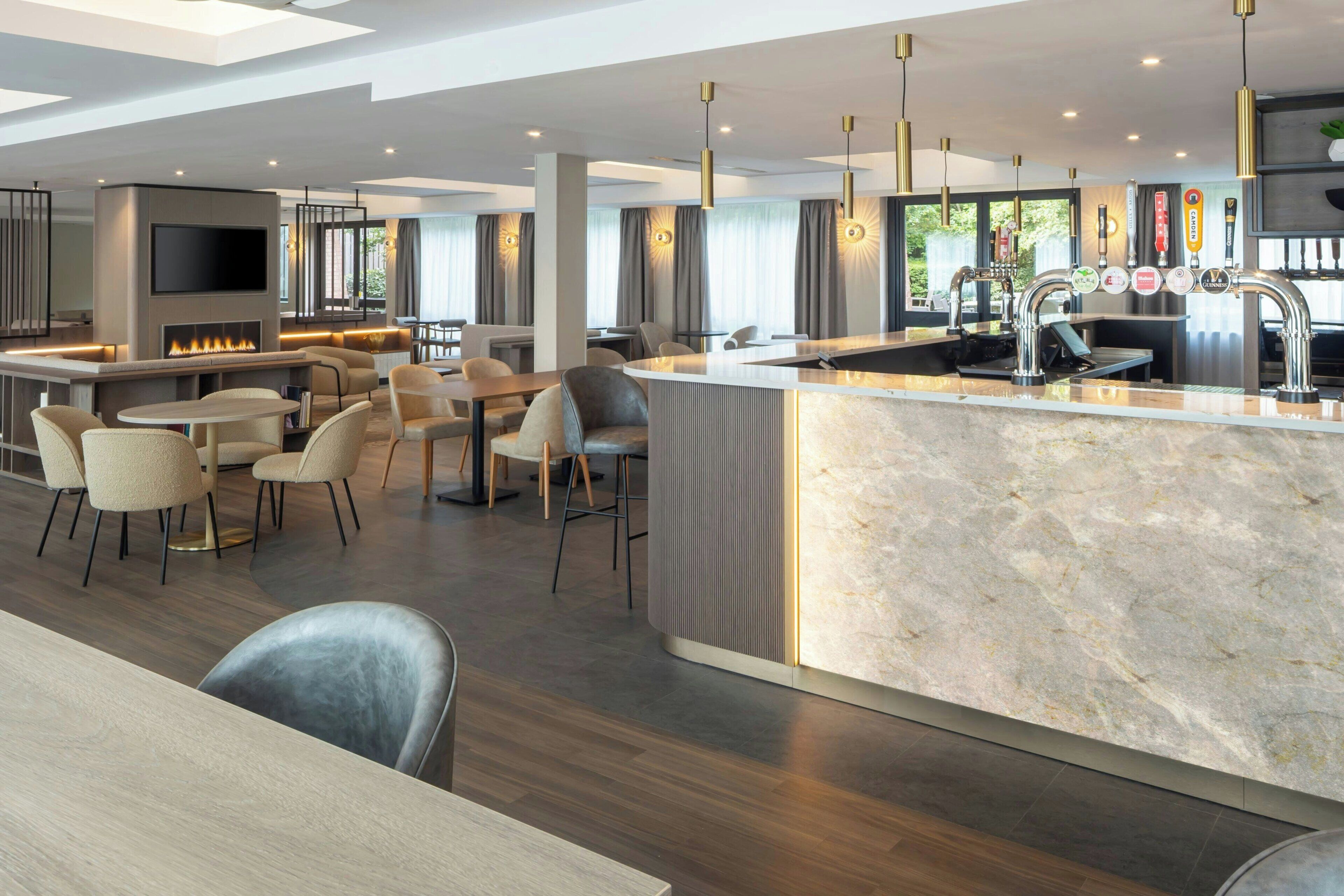 A modern kitchen with a marble countertop, a built-in TV, and a bar area with multiple taps.