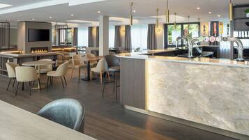 A modern kitchen with a marble countertop, a built-in TV, and a bar area with multiple taps.