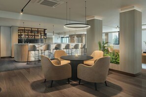 A modern kitchen with bar seating, a round dining table with chairs, and a vertical garden. - AC Hotel Birmingham NEC and Airport (Birmingham)