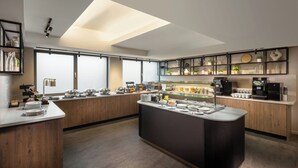 Une cuisine moderne dotée d’un îlot central, d’appareils électroménagers intégrés et d’une grande fenêtre qui laisse entrer la lumière naturelle.