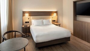 Une chambre d’hôtel avec un grand lit, deux tables de chevet, une télévision et une chaise.