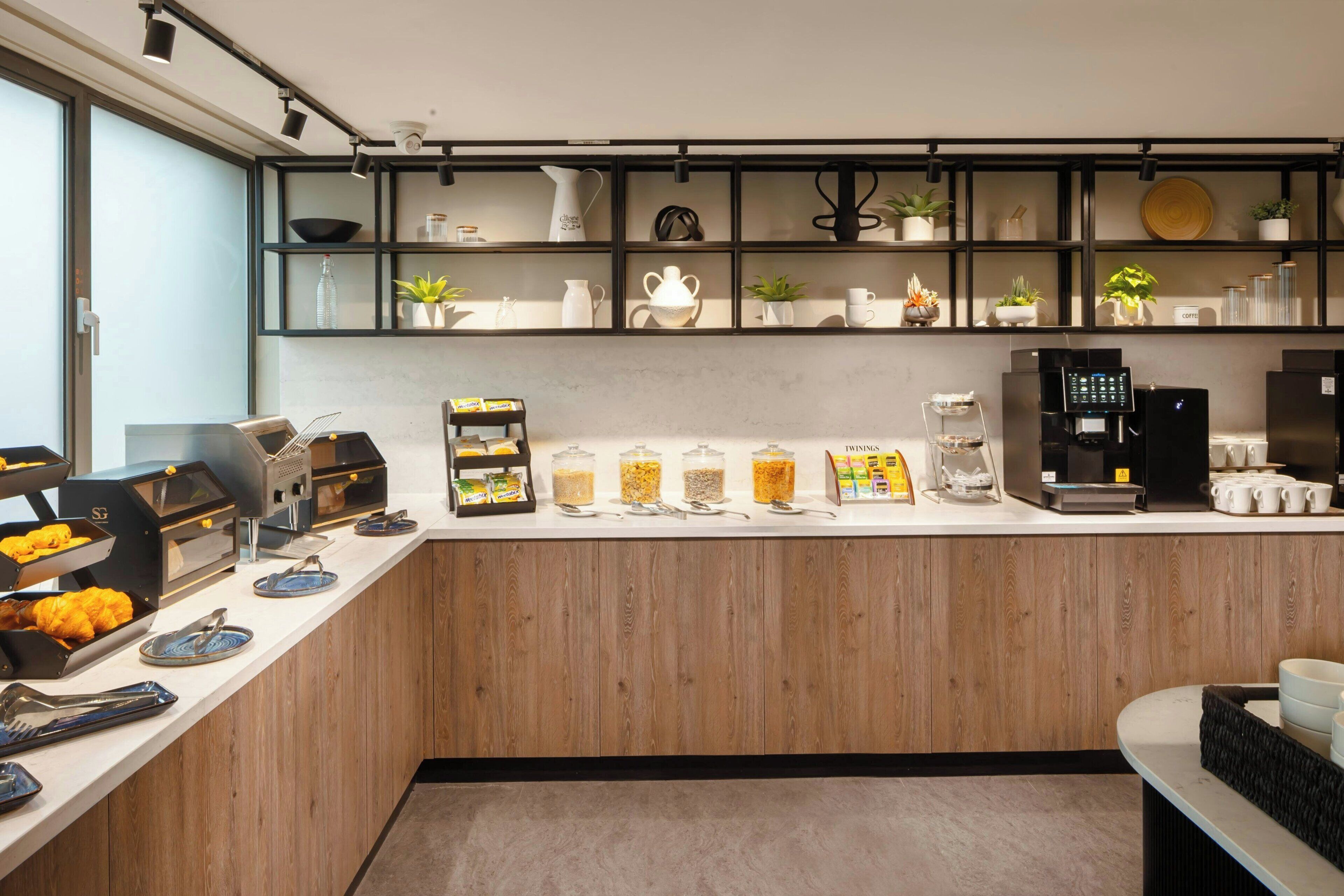 Una cocina moderna con mostrador de madera, máquinas de café y varios electrodomésticos.