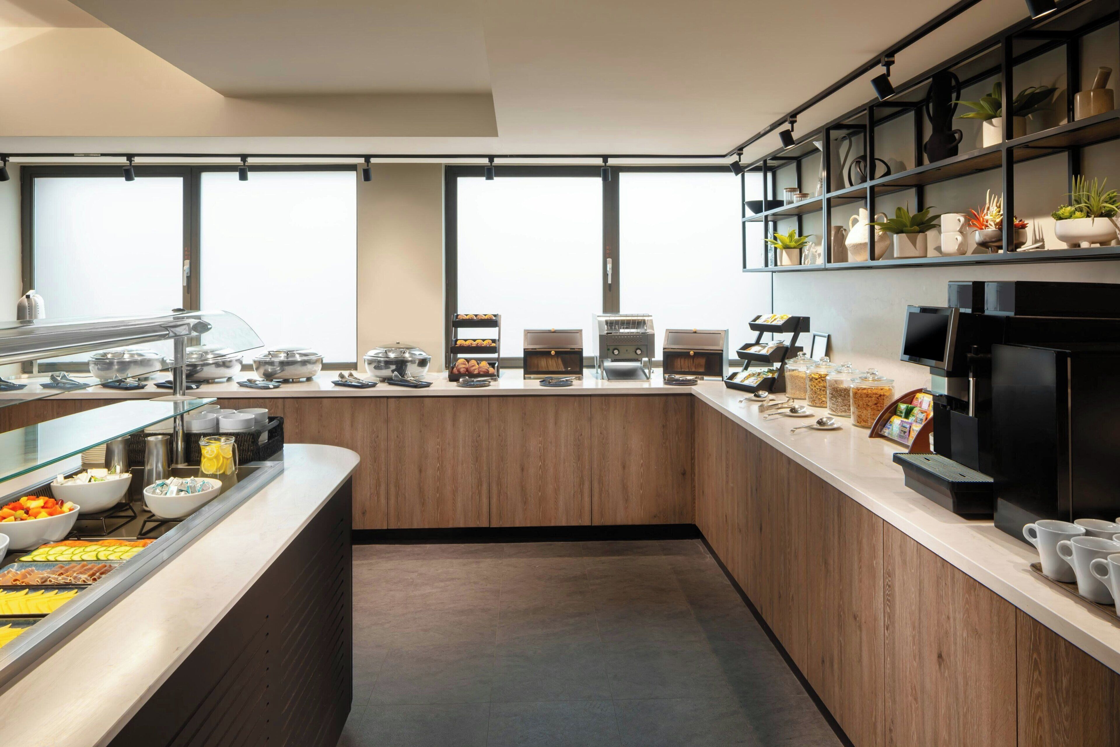 A modern breakfast bar with a variety of food options, a coffee station, and a black refrigerator.