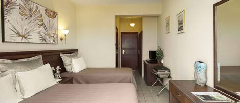 A hotel room with two beds, a desk with a computer, a TV, and a large mirror.