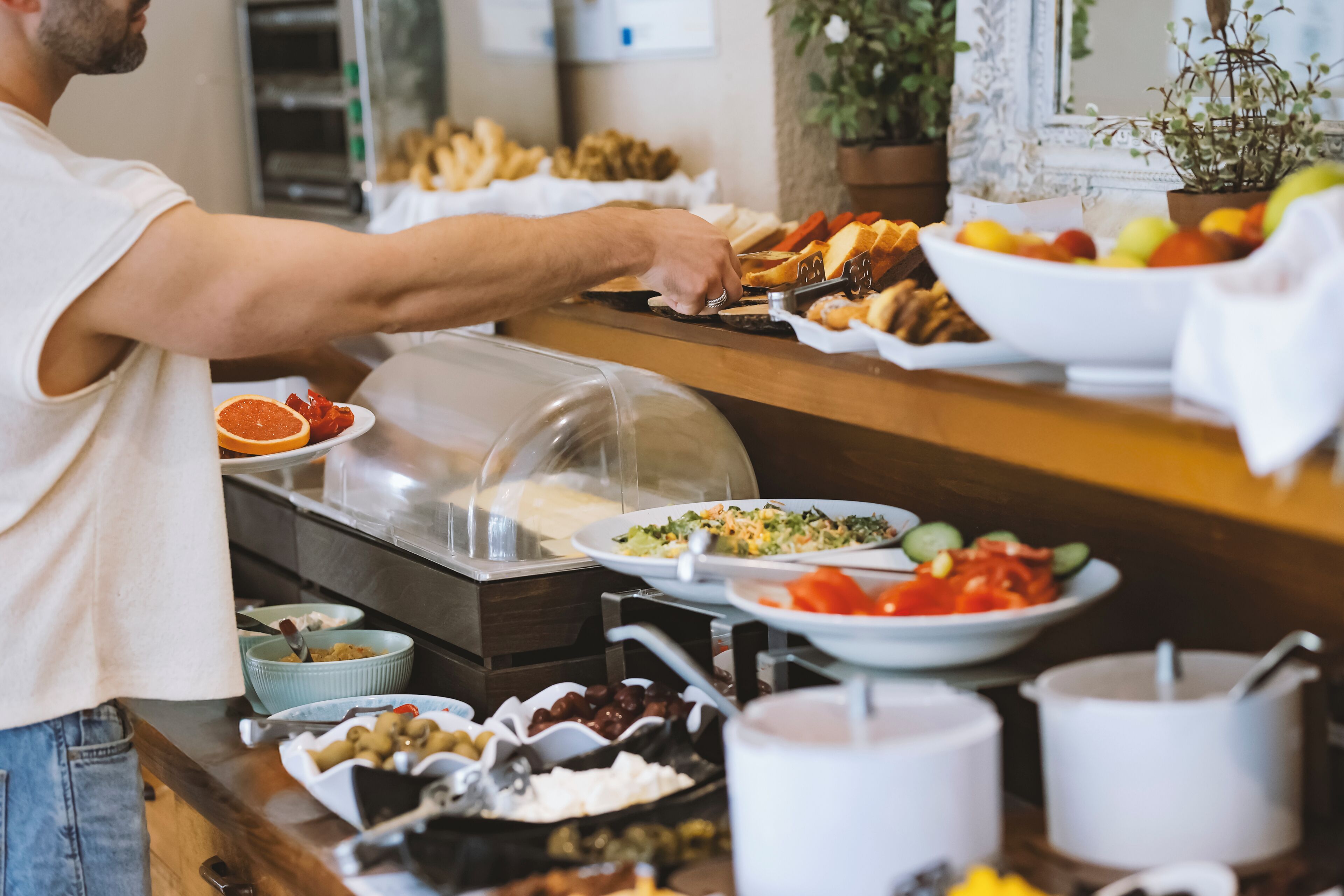 A buffet setup with various food items and a person serving.
