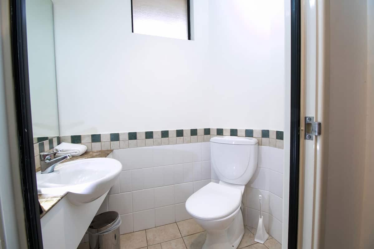 Un baño pequeño con lavamanos, inodoro y espejo blancos.