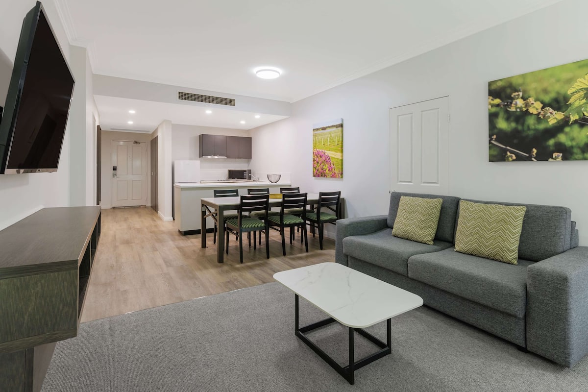 Una sala de estar moderna con un sofá gris, una mesa de centro blanca y un comedor con una mesa y sillas.