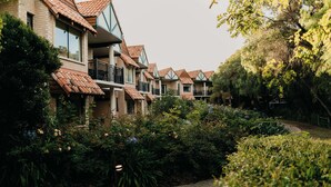A row of brick buildings with red-tiled roofs, surrounded by lush greenery and a paved walkway. - Club Wyndham Dunsborough, Trademark Collection by Wyndham (Marybrook)