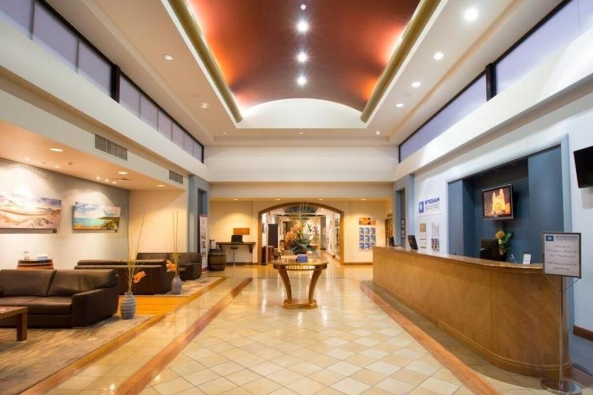 A hotel lobby with a reception desk, seating area, and a large window.
