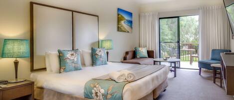 Ein Hotelzimmer mit einem großen Bett, einem Schreibtisch, einem Stuhl und einem Balkon mit Blick ins Freie.