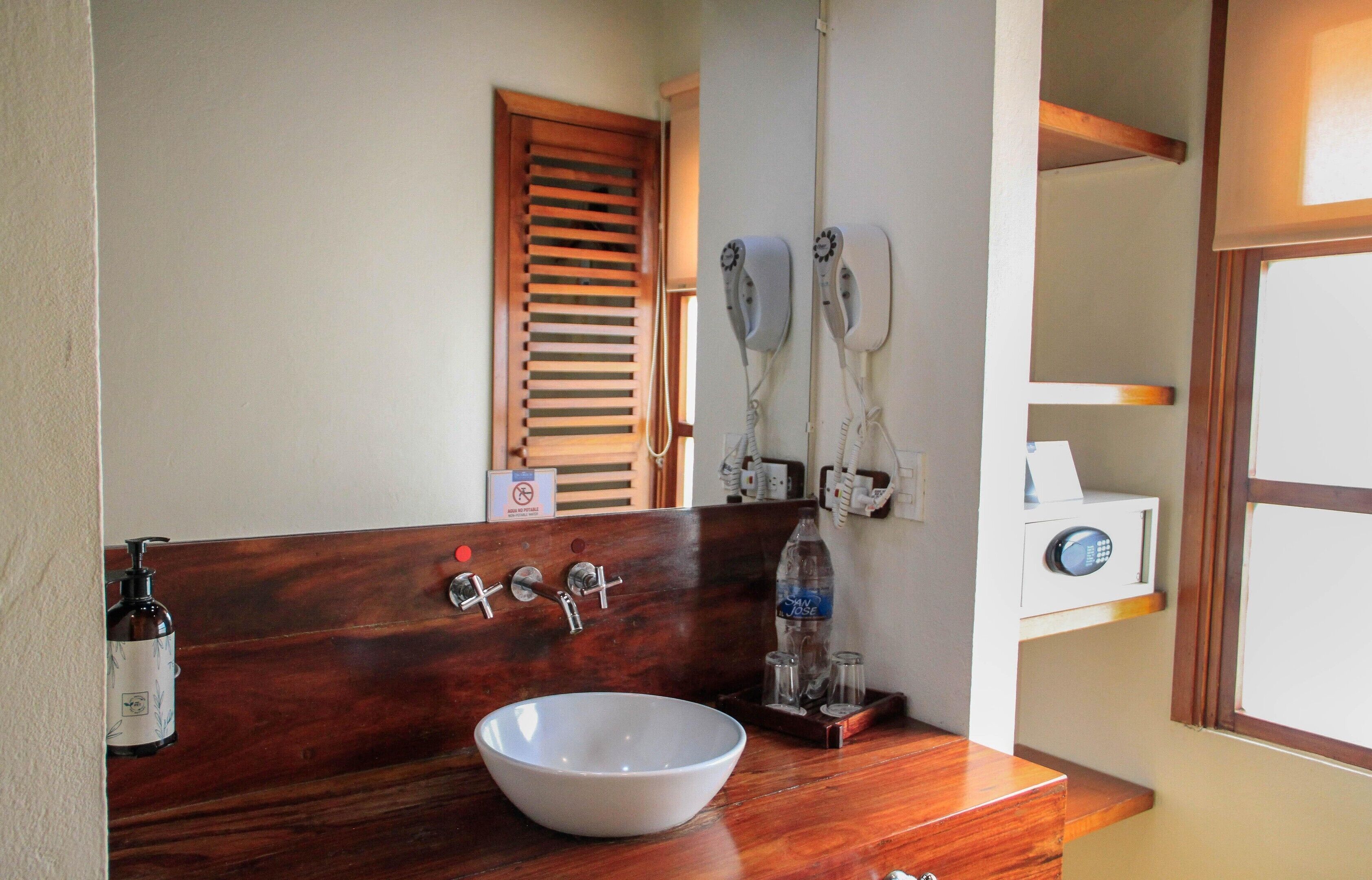 A bathroom with a wooden vanity, a white sink, and a mirror.