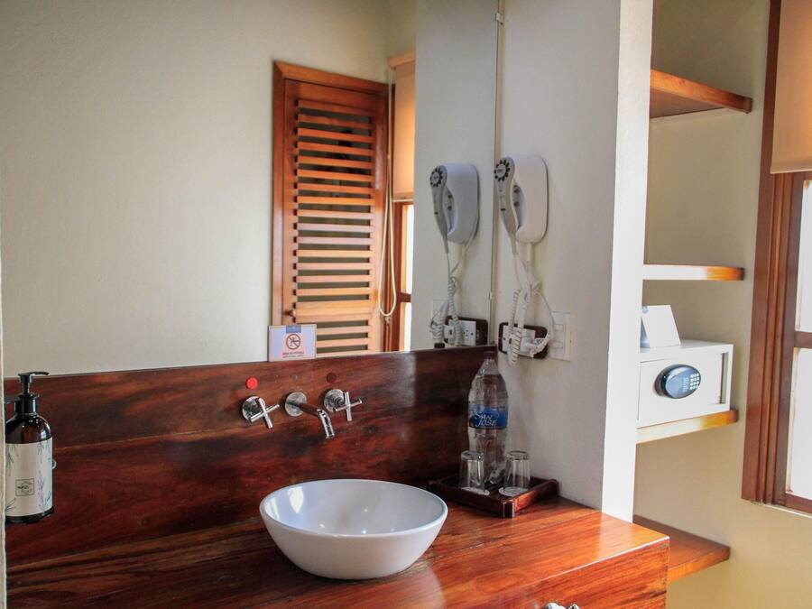 A bathroom with a wooden vanity, a white sink, and a mirror.