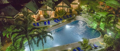 Una piscina al aire libre, sillones reclinables de piscina