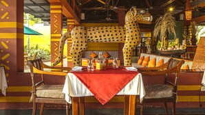 A restaurant with a wooden ceiling, a table with a red tablecloth, and chairs. - Decameron Decalodge Ticuna (Leticia)