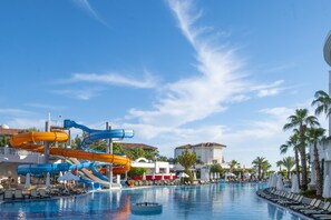 Ett poolområde på ett semesterhotell med flera vattenrutschkanor och solstolar.