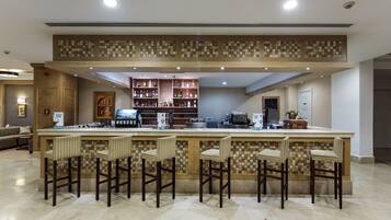 A bar area with a checkered tile backsplash, bar stools, and a variety of liquor bottles.
