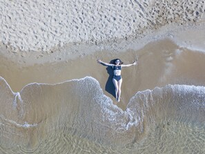 Na praia, espreguiçadeiras, guarda-sóis, toalhas de praia 