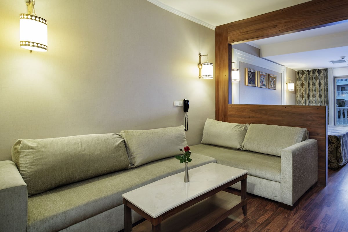 Una sala de estar con sofá, mesa de centro y comedor con una mesa lista para dos.