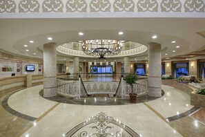 A spacious lobby with a grand chandelier, a reception desk, and a circular seating area with a potted plant. - Alba Queen Hotel - Ultra All Inclusive (Manavgat)