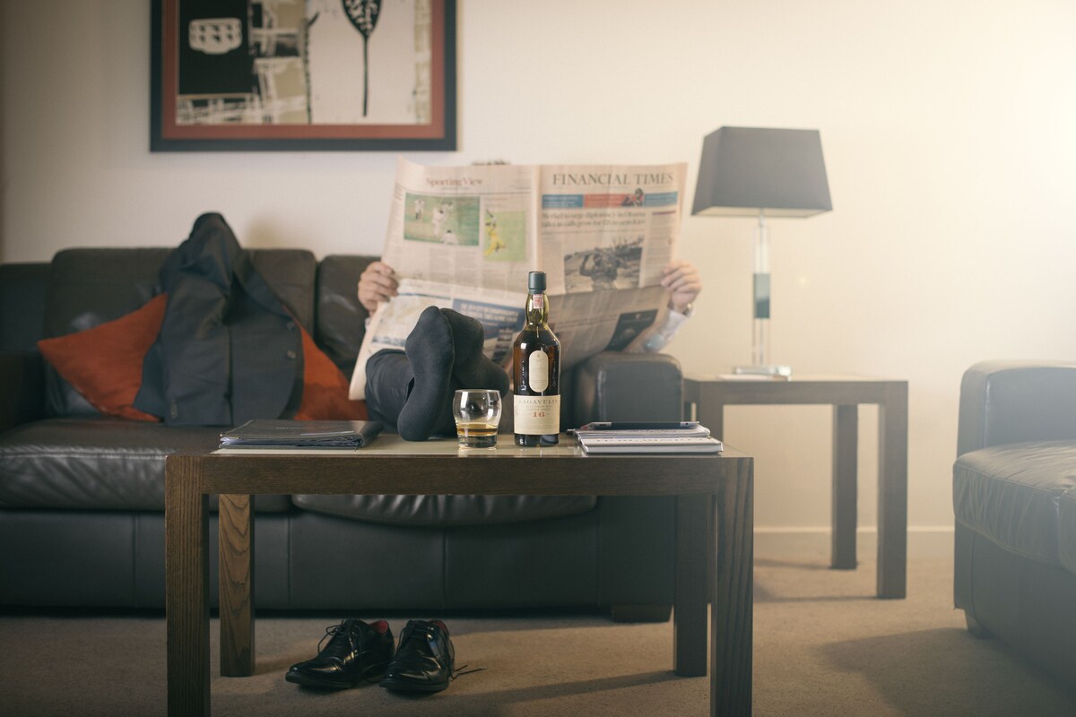 A living room with a sofa, a coffee table, and a newspaper.