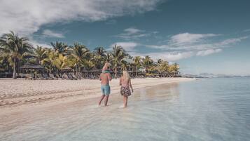Una playa con agua cristalina, palmeras y sillas de descanso.