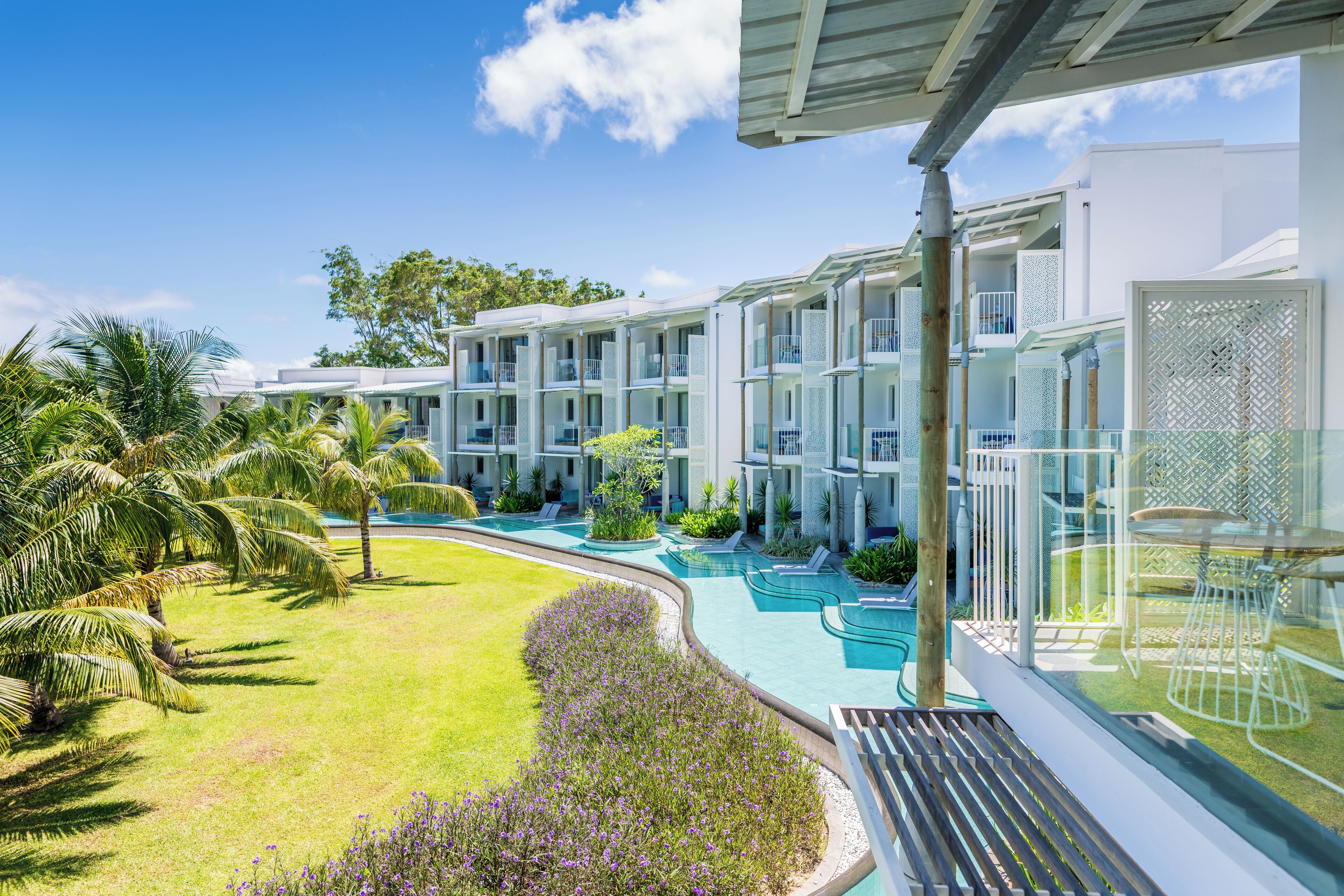 Un resort con edificios de varios pisos, una piscina y palmeras.