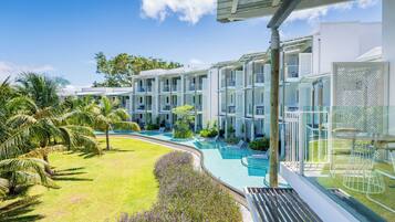 Un resort con edificios de varios pisos, una piscina y palmeras.