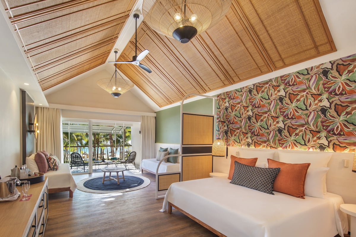 Un dormitorio amplio con una cama grande, una zona de comedor y vistas al área de la piscina exterior.