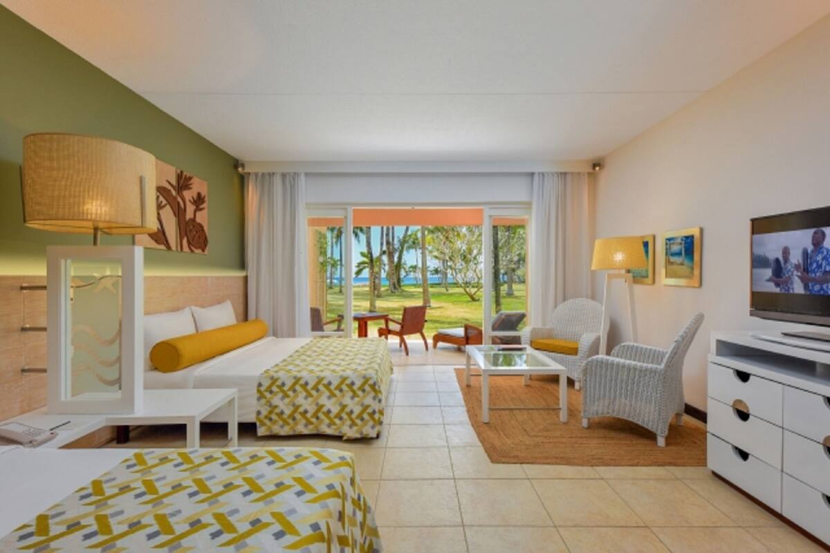 Una habitación de hotel con una cama, un sofá, un televisor y vistas al exterior.