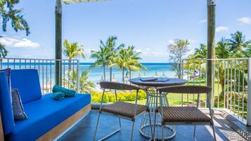 Un balcon avec un canapé bleu, des fauteuils en osier et une petite table ronde.