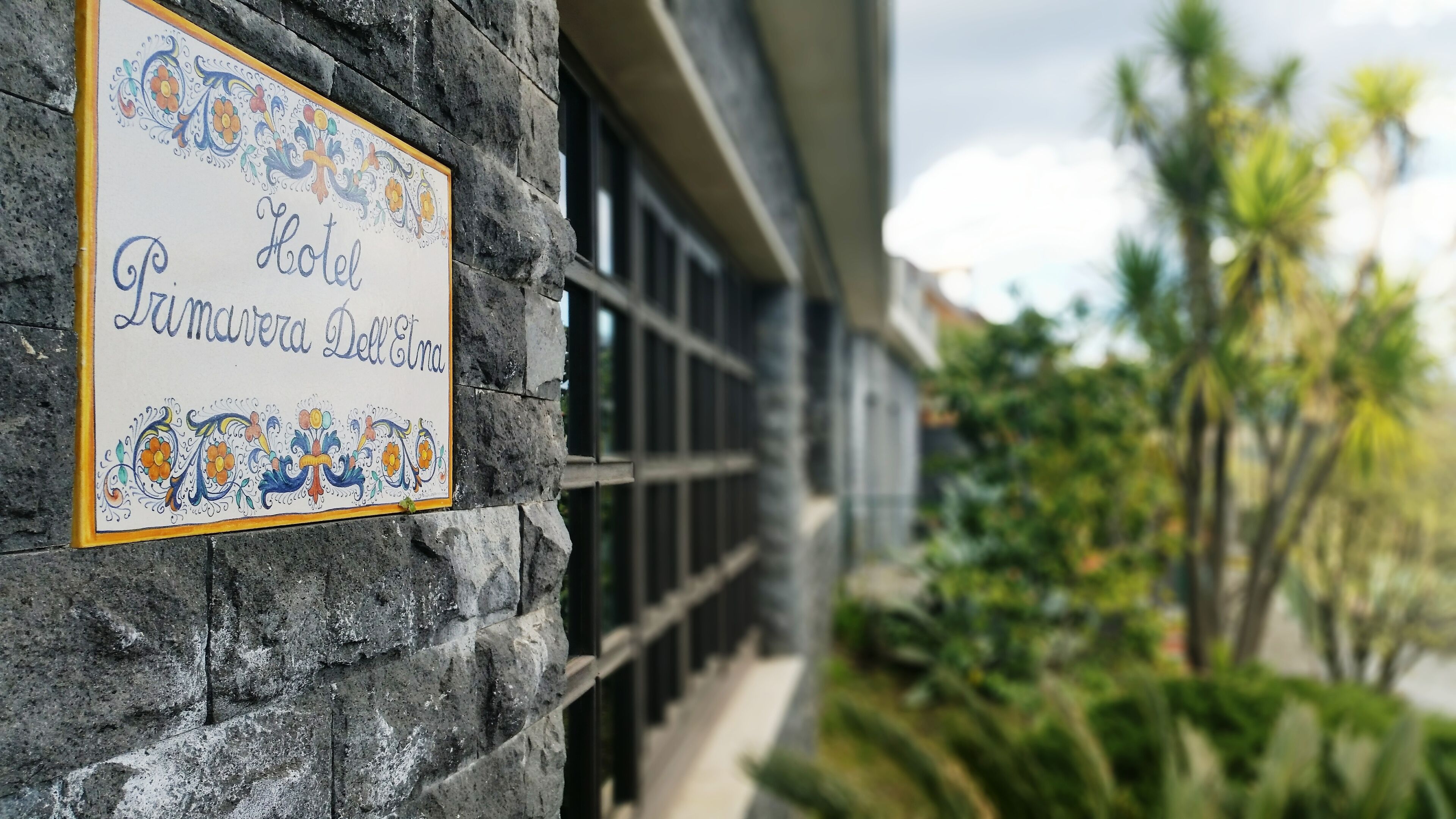 A hotel sign with decorative floral patterns and the name "Hotel Lumavera Dell'Etna".