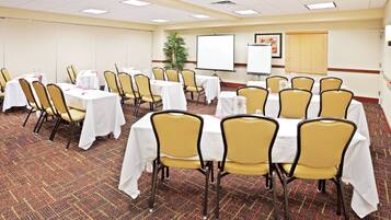 A conference room with tables and chairs, a whiteboard, and a projector screen.