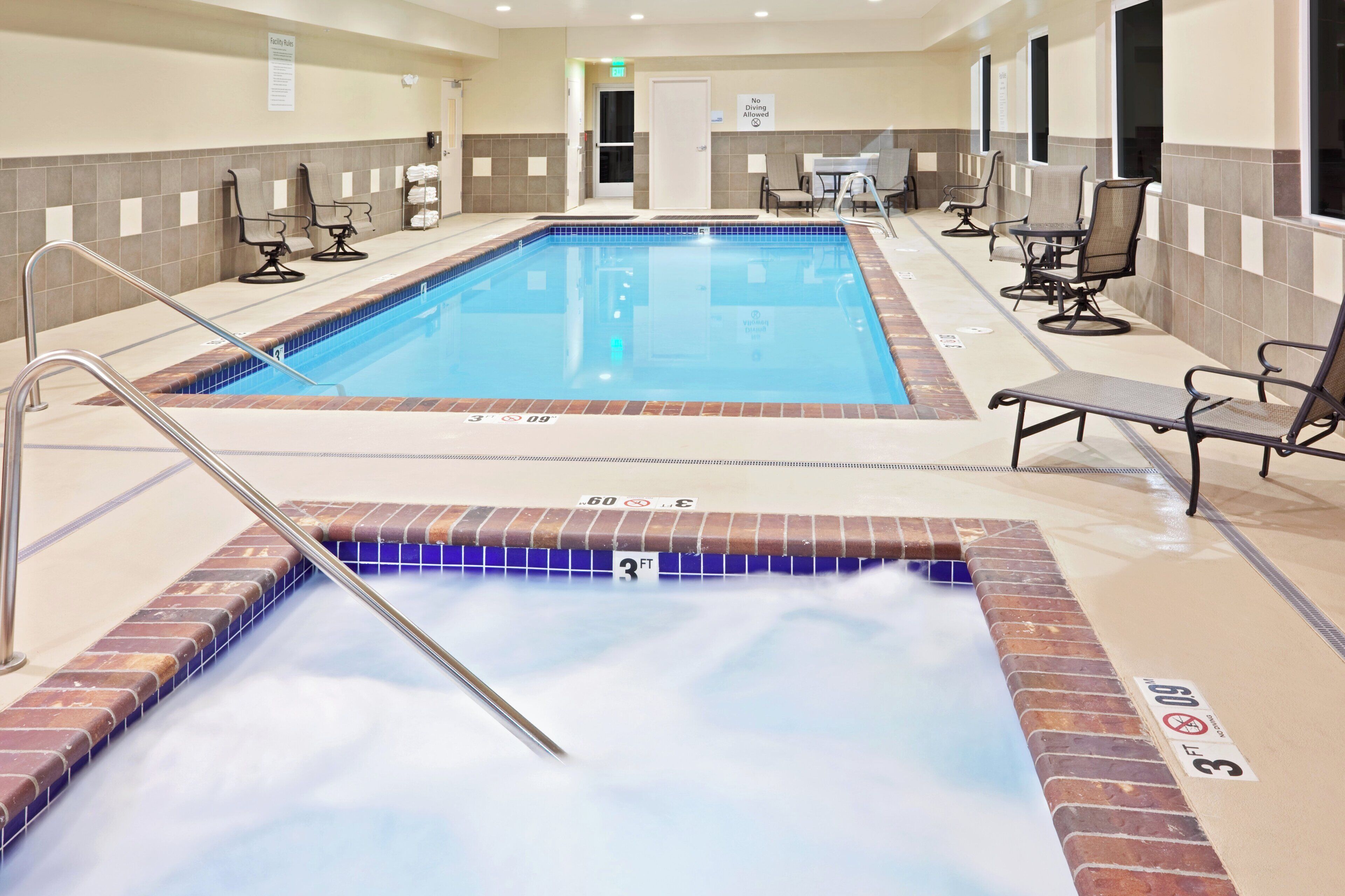 A swimming pool with a hot tub, lounge chairs, and a sign indicating no diving is allowed.