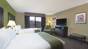 A hotel room with two beds, a TV, a desk, and a chair.