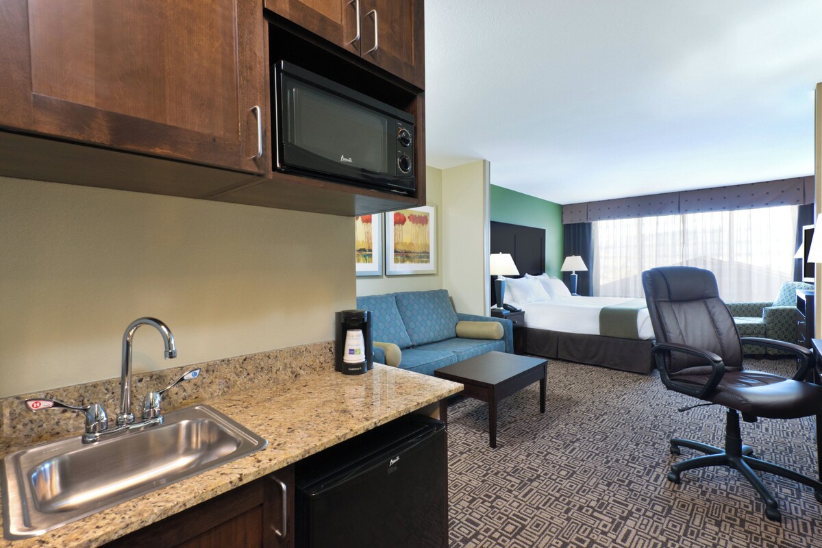 Une chambre d’hôtel équipée d’une kitchenette, d’un lit, d’un canapé, d’un bureau et d’une chaise.