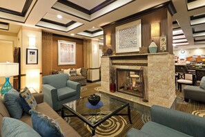A hotel lobby with a fireplace, seating area, and a dining section.