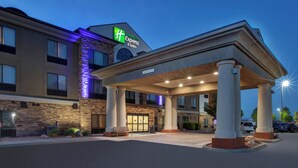 A Holiday Inn Express & Suites building with a stone facade, large columns, and a covered entrance area.