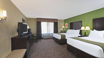 A hotel room with a bed, a desk with a television, a chair, and a window with curtains.