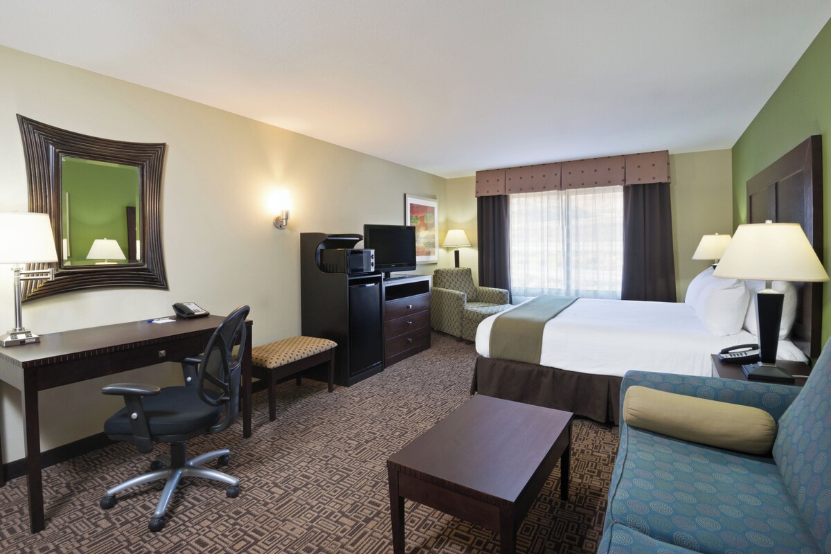 Une chambre d’hôtel équipée d’un bureau, d’une chaise, d’un lit, d’un canapé et d’une télévision.