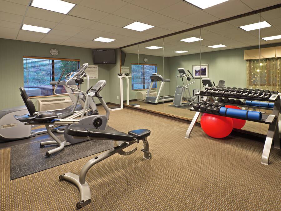 A gym with various exercise equipment, including treadmills, an elliptical, and a weight bench.