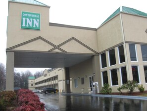 A Continental Inn building with a large entrance canopy, multiple windows, and a parking lot with cars.