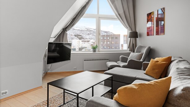 Una sala de estar moderna con un sofá, una mesa de centro y un televisor montado en la pared.